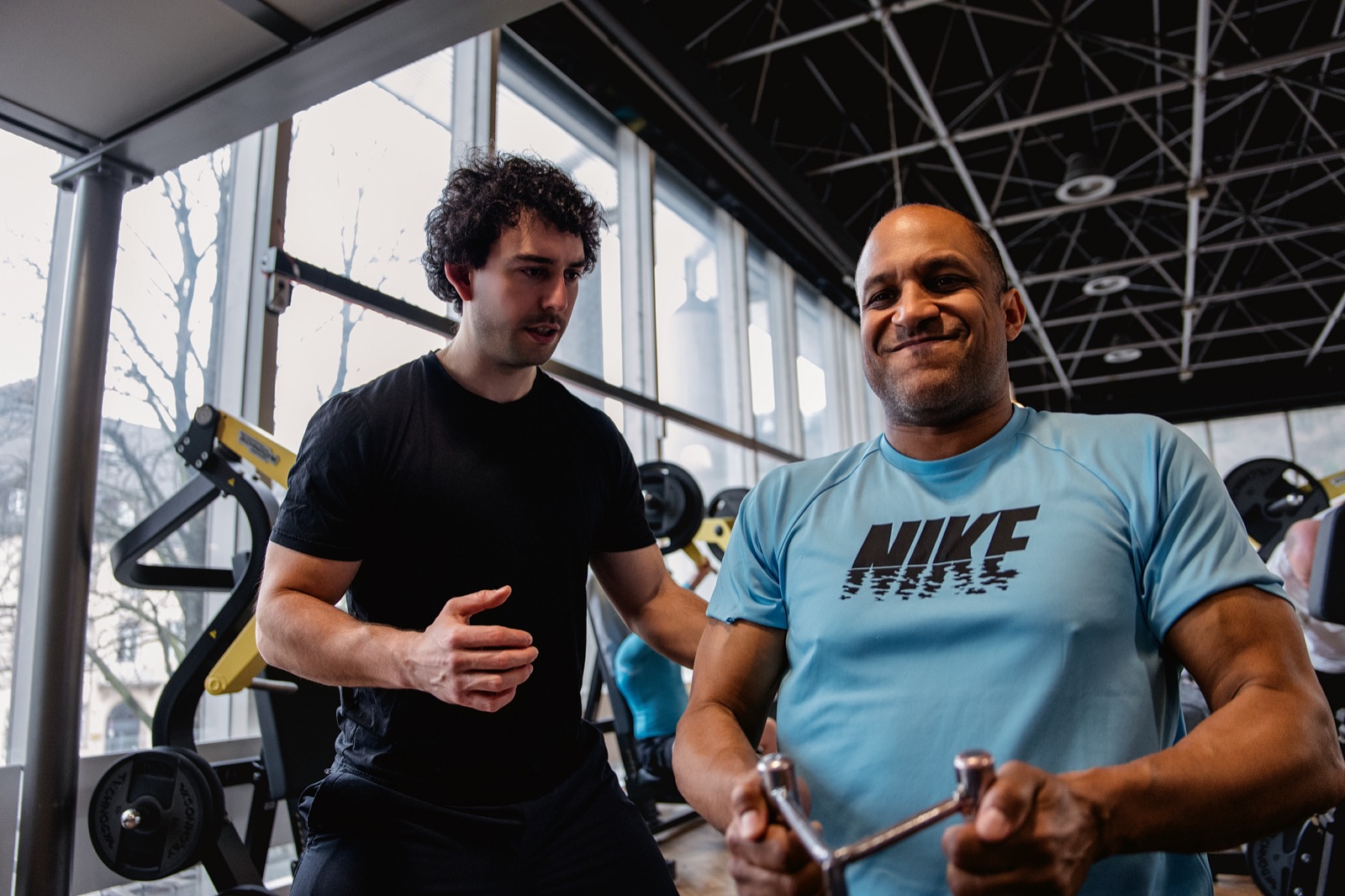 Patrick Detta erklärt einem Kunden eine Übung im Fitnessstudio